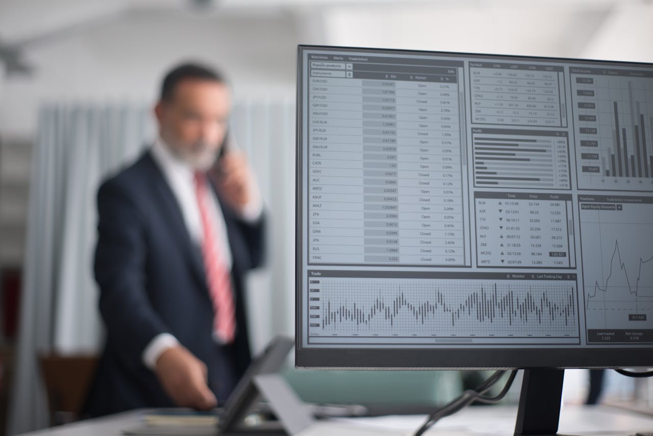 Professional analyzing financial and stock market data on a computer screen in an office setting.